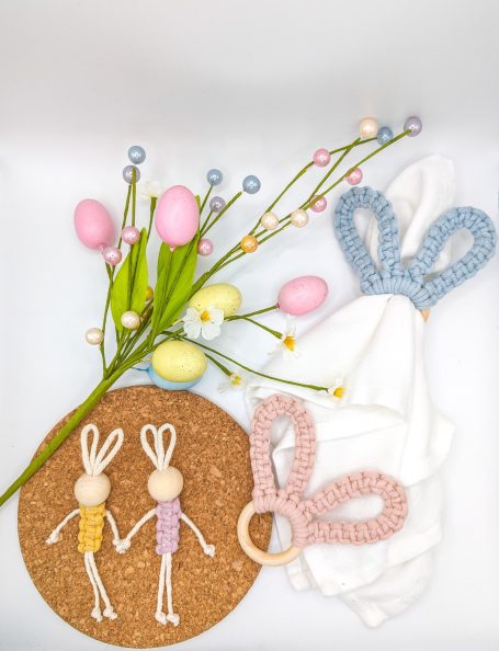 Colourful Easter decorations featuring crafted bunnies, pastel eggs, and flowers on a cork base.