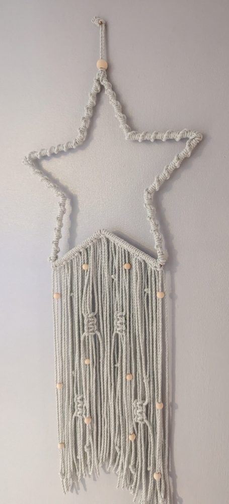 A pale blue star-shaped decoration with hanging tassels.
