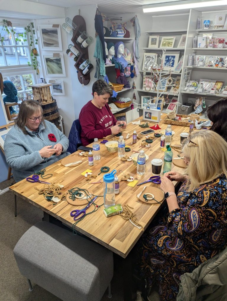 Group of women engaged in a crafting activity around a wooden table.