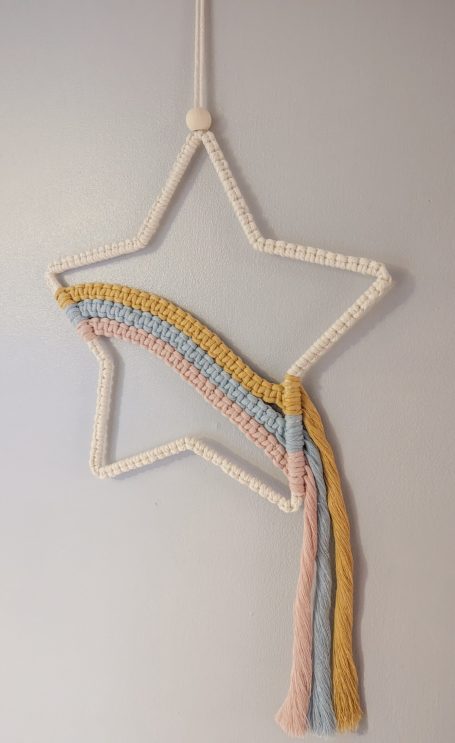 A star-shaped wall hanging with pastel-coloured rainbow strands trailing down.