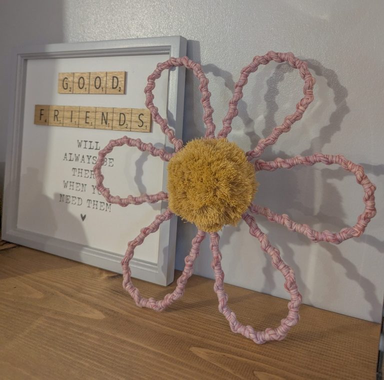 A whimsical craft flower with a yellow centre and pink twisted petals.