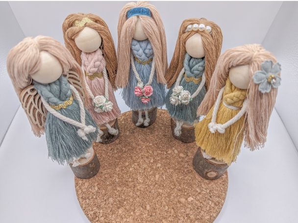 Five handmade dolls with long hair, dressed in various coloured outfits, arranged in a circle.