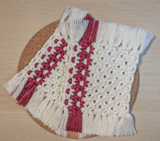 Handcrafted decorative square coasters with white and burgundy woven patterns and fringed edges.