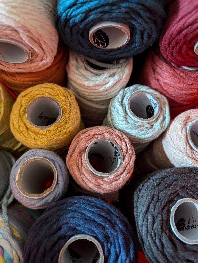 A collection of variously coloured yarn spools stacked together.